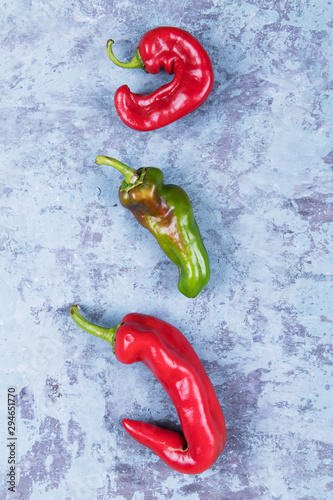 Three ugly red chili peppers on a blue grunge background, minimal style, creative food concept photo