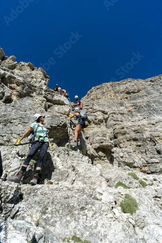 mountain guide and several clients climbing a Via Ferrata in the Italaian Dolomites