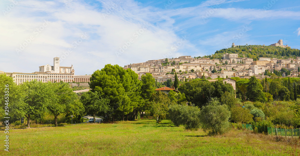 Panoramic view from countryside of the historic town of Assisi in beautiful sunny day with blue sky and clouds in summer, Umbria, Italy.
