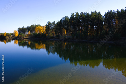 Lake in a delightful autumn forest at sunny day. Autumn trees with reflection. Russia. 