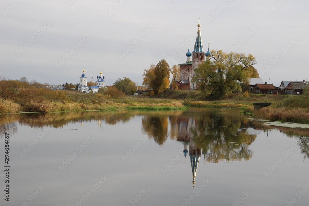 church on the river reflecting in calm water in sunny fall day
