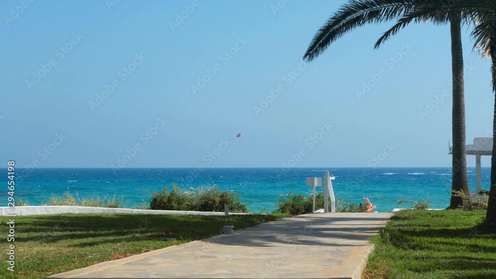 Path with palms leading to the beach of the azure mediterranean sea and surrounded by a beautiful nature of Cyprus. Ayia Napa.