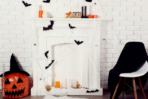 Halloween decorations on white fireplace with orange pumpkin and chair photo