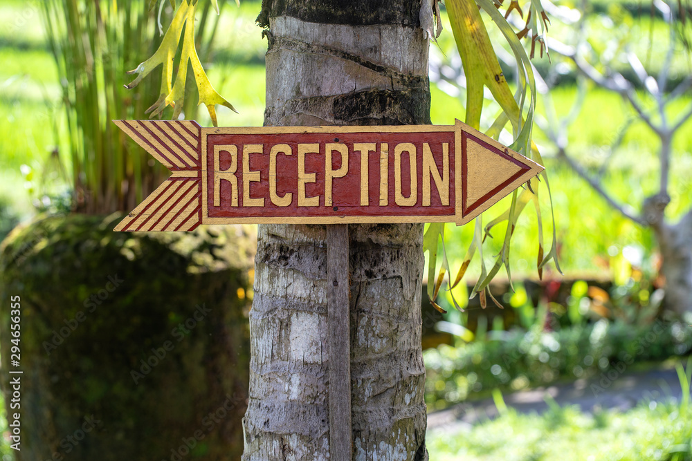 Text reception on a wooden board near tropical hotel in Bali island, Indonesia. Reception wooden sign inscription in the asian tropics, closeup