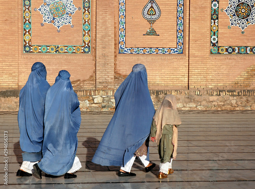 Herat in western Afghanistan. The Great Mosque of Herat (Friday Mosque or Jama Masjid). Three women in burqas and a girl walk at the front of the mosque. The mosque is one of the oldest in Afghanistan