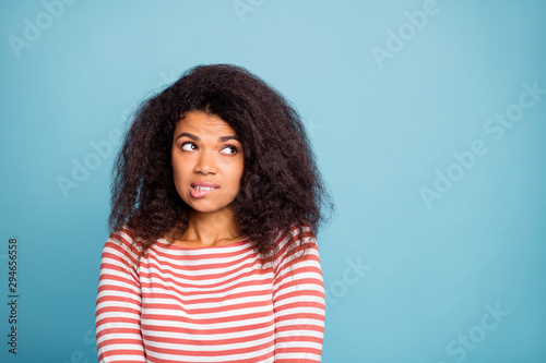 I'm so sorry. Photo of pretty dark skin lady looking empty space with guilty eyes biting lips apologizing wear casual clothes isolated pastel blue color background photo