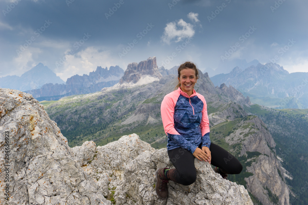Obraz premium attractive brunette mountain climber sitting on a mountain peak and smiling