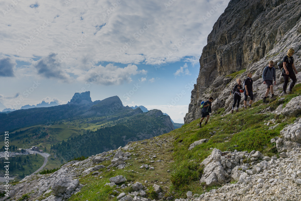 Naklejka premium group of mountain climbers hiking up a mountain side to a hard climbing route