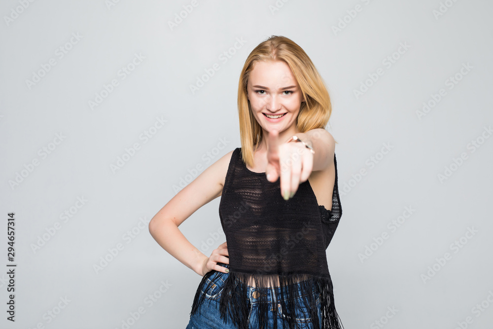 Confident beauty choosing you. Waist up of attractive young woman showing her thumb up and smiling while standing against grey background