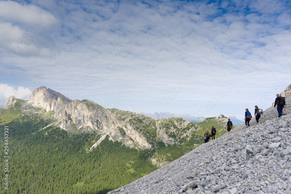 panorama of a group of mountain climbers hiking up a mountain side to a hard climbing route