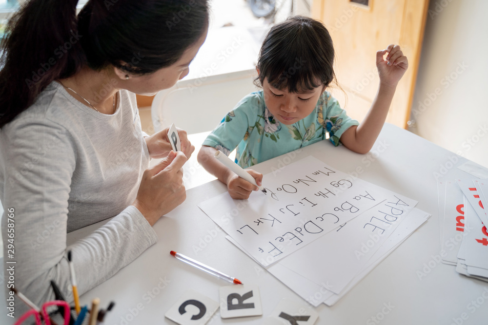 happy mother teaching her daughter the basic to read and write at home. toddler kindergarten student happy mother teaching her daughter the basic to read and write at home. toddler kindergarten student