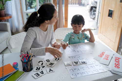 Tableau sur toile mother and daughter learning to read and write letter at home together