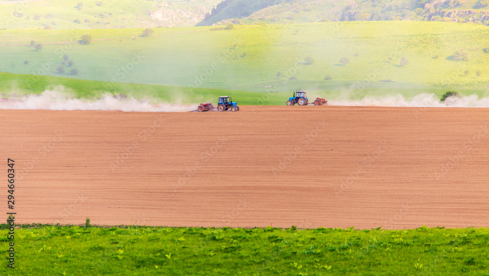 Obraz premium Dust from a tractor working in a field in spring
