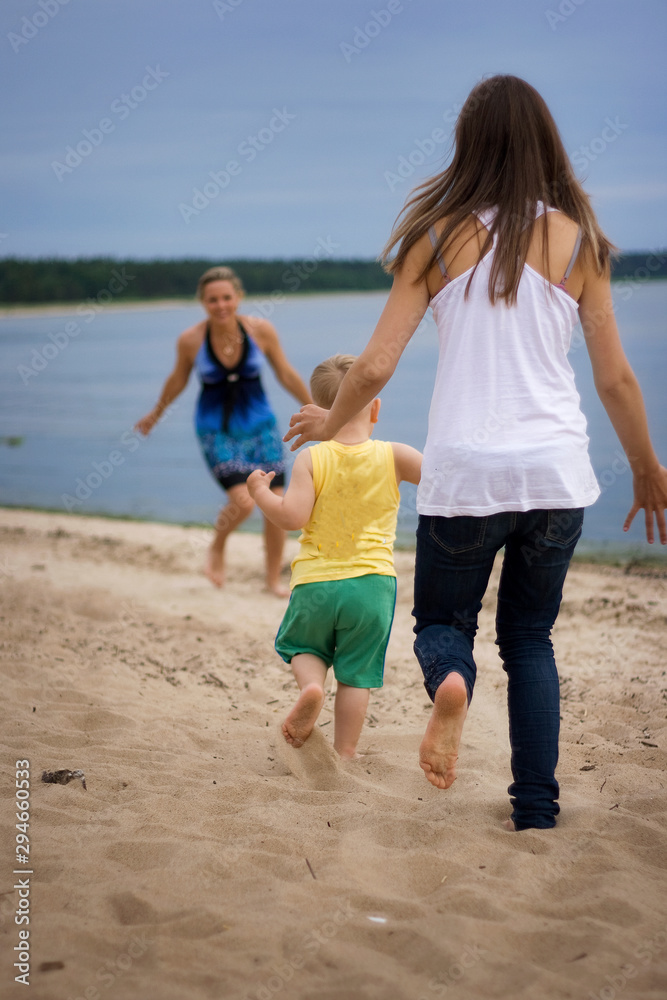 Mother and son running on the beach. Concept of family life and summer vacations