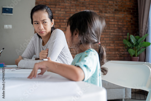Foto portrait of unhappy mother while teaching her daughter at home