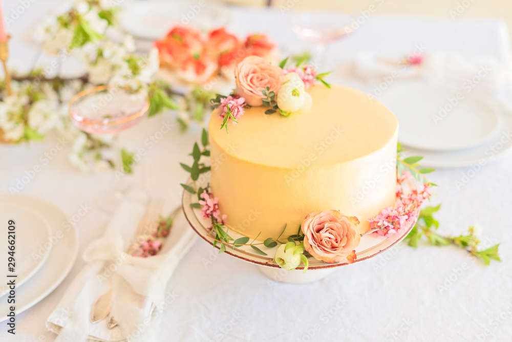 Wedding cake with flowers without piece on boho style table setting.