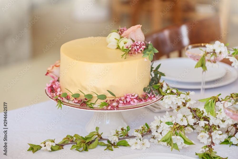 Wedding cake with flowers, boho style table setting. Holiday cake on table Wedding cake with flowers, boho style table setting. Holiday cake on table