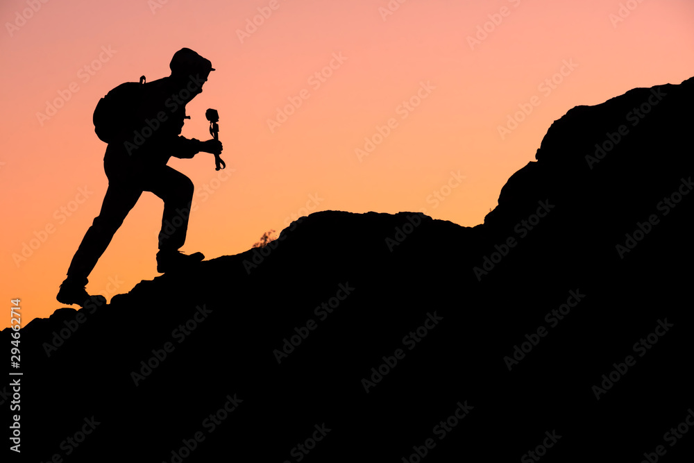 silhouette of a traveler walking with a backpack on the mountains in the camera and tripod silhouette of a traveler walking with a backpack on the mountains in the camera and tripod