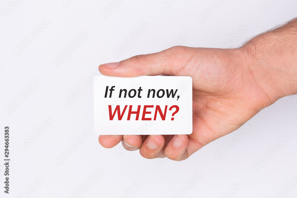 If not now, when?The hand holds a card with the inscription. White background. Copy space If not now, when?The hand holds a card with the inscription. White background. Copy space