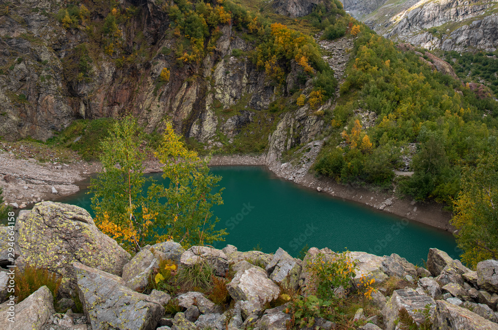 A green lake surrounded by mountains and autumn forest. Turye lake in Dombay.
