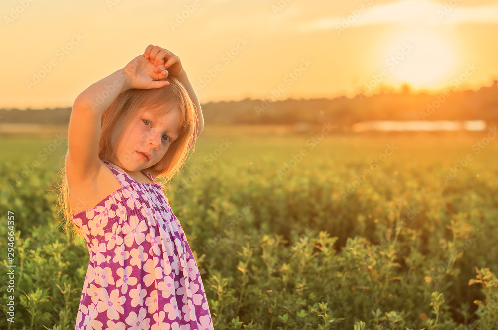 Сute little red-haired girl with freckles in a field at sunset Сute little red-haired girl with freckles in a field at sunset