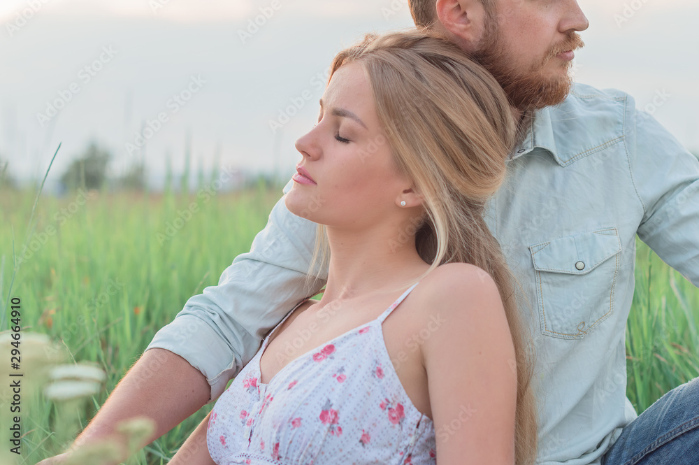 Obraz premium Love story of the beautiful bearded man and woman on green summer meadow
