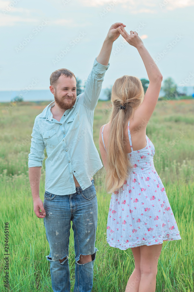 Love story of the beautiful bearded man  and womanc are dancing on the green summer meadow