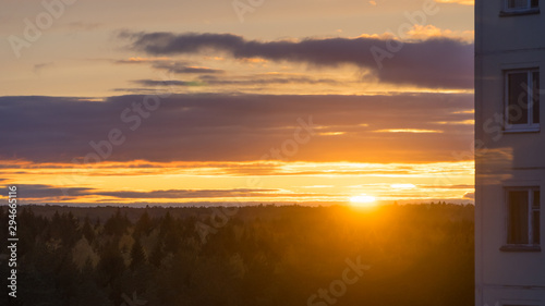 Beautiful orange sunset sky with clouds and sunlight over forest horizon