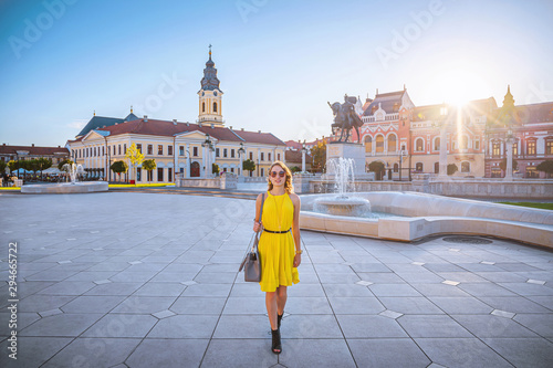 Tableau sur toile Beautiful woman walking in the sunset with a yellow dress in the historioc europ