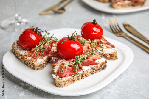 Plate of delicious bruschettas with prosciutto on grey table