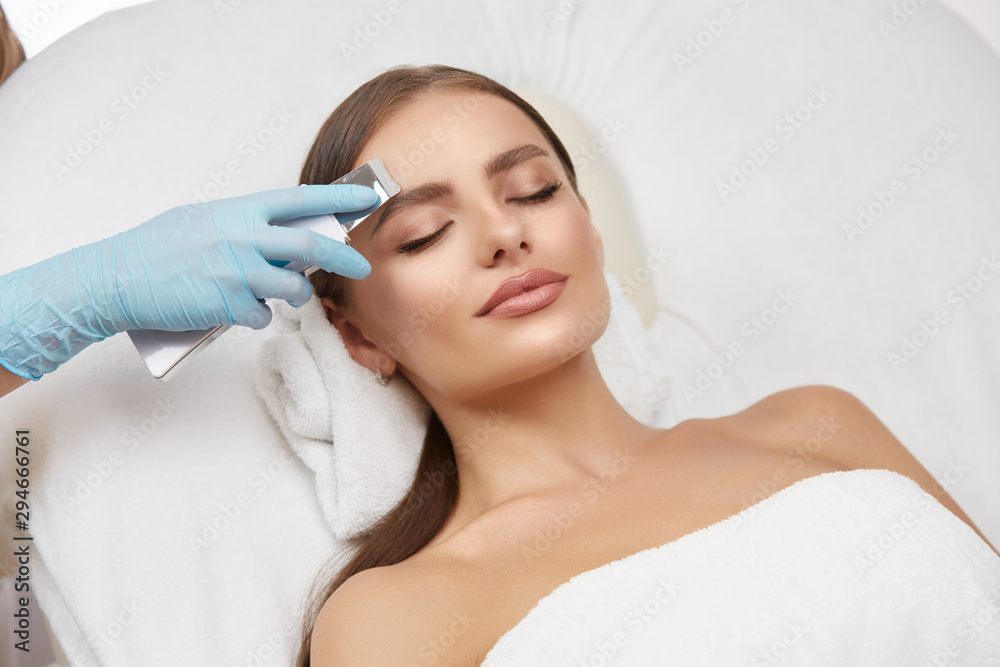 Cosmetology. Closeup Of Female Face having facial treatment in beauty salon. Cosmetic procedures in spa clinic.