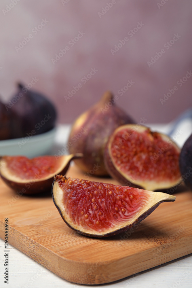 Wooden board with tasty ripe figs on white table, closeup Wooden board with tasty ripe figs on white table, closeup
