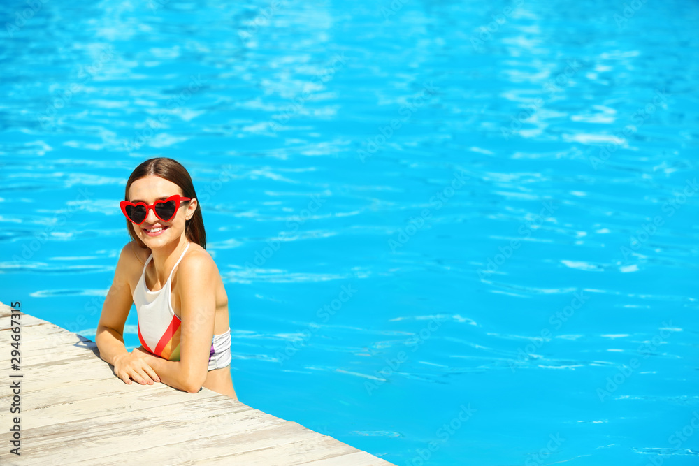 Beautiful young woman in swimming pool on sunny day
