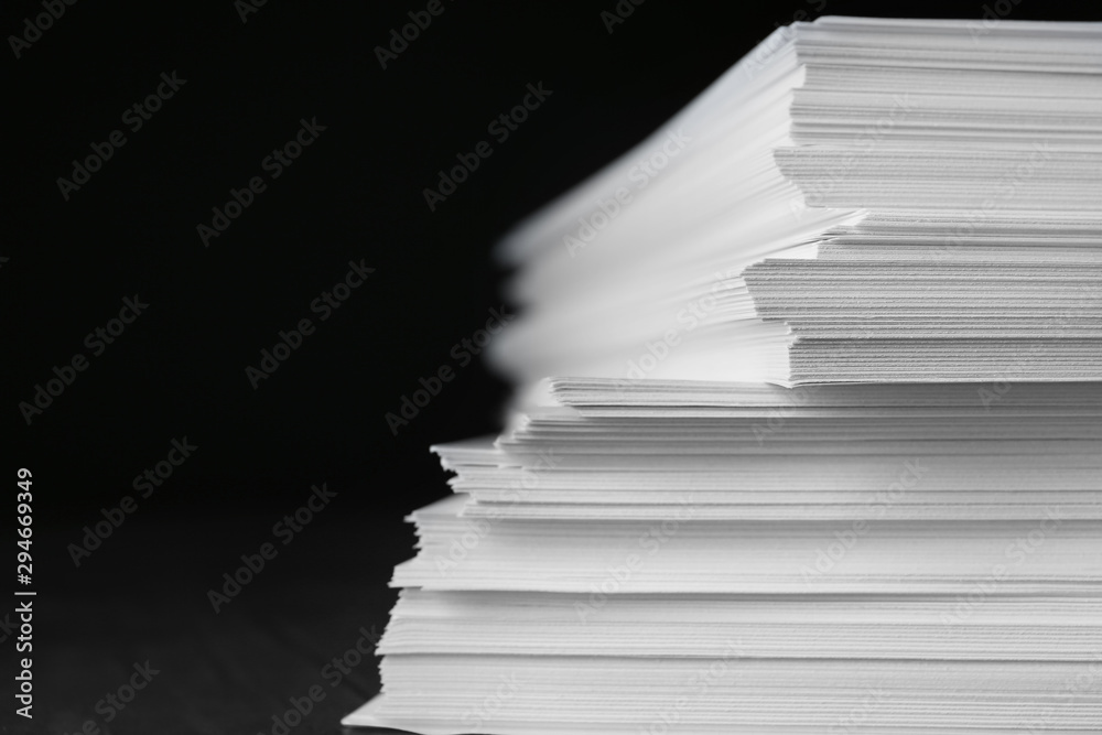 Stack of blank paper on table against black background, closeup - obrazy, fototapety, plakaty 