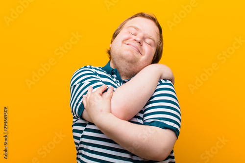 Fotografía young big size man feeling in love, smiling, cuddling and hugging self, staying