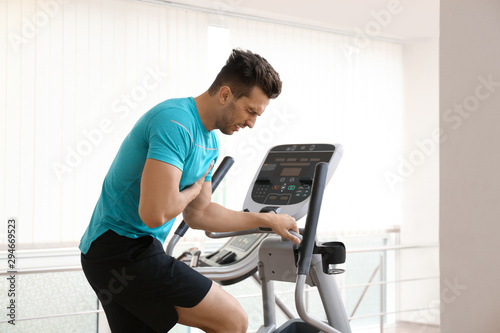 Young man having heart attack on treadmill in gym
