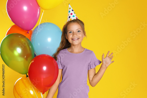 Happy girl with balloons on yellow background. Birthday celebration
