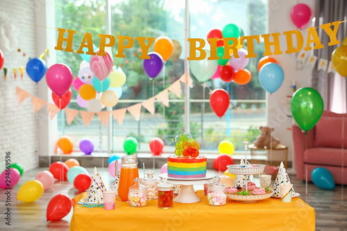 Canvas Print Bright birthday cake and other treats on table in decorated room