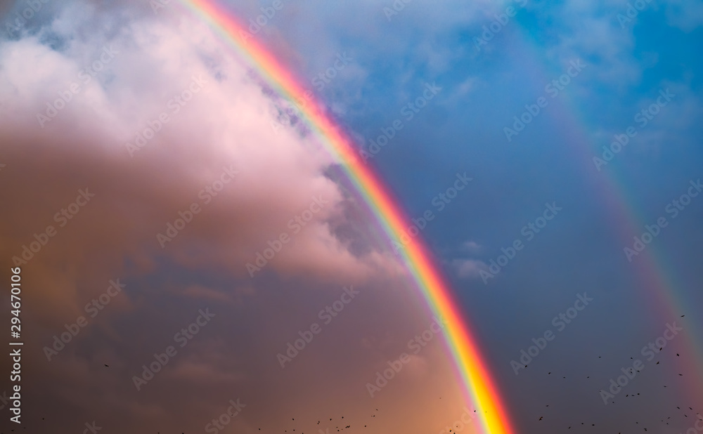 double rainbow in the sky with clouds and birds