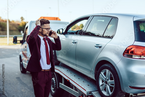 Elegant middle age business man calling towing service for help on the road. Roadside assistance concept. © hedgehog94