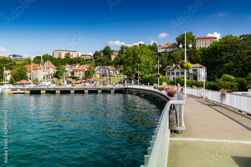 View of the pier, buildings and port in the city of Thonon les Bains on Lake Geneva in the background the blue sky.
