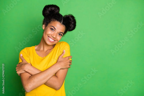 Photo of pretty dark skin lady holding herself in hugs toothy beaming smiling overjoyed wear casual yellow t-shirt isolated green background