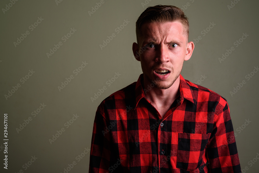Obraz premium Young man wearing red checkered shirt against colored background