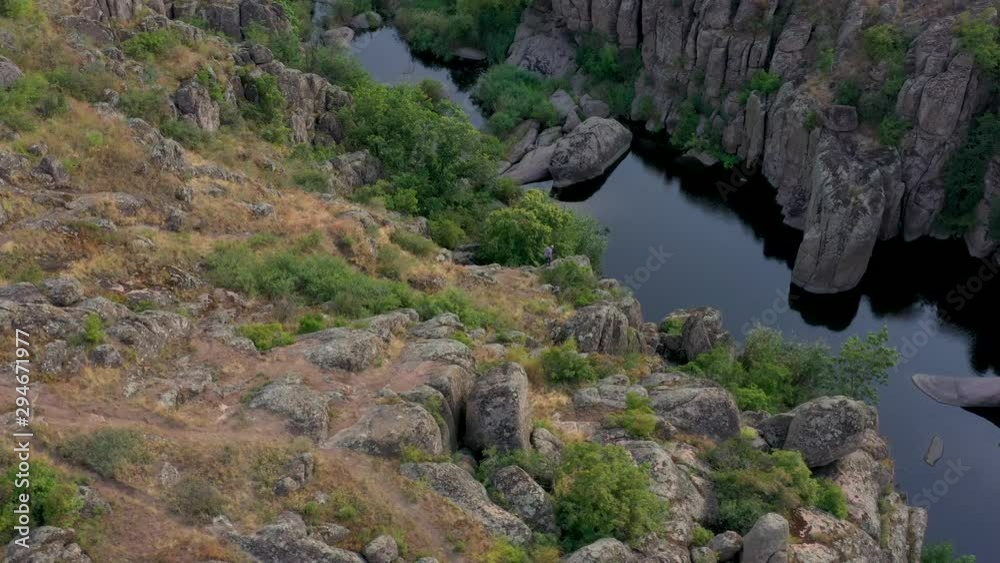 Eldery man walking in canyon over river. Dron camera shooting Eldery man walking in canyon over river. Dron camera shooting