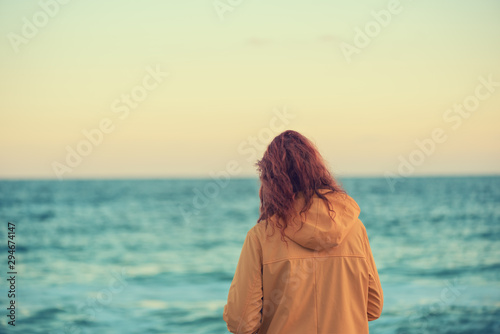 Great pleasure. Charming calm young woman is standing near sea with closed eyes and expressing delight. She is posing against wonderful sunset while enjoying last rays of the sun © iwavephoto