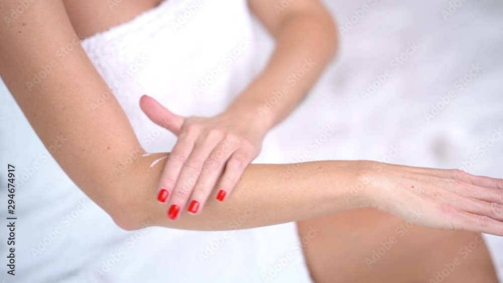 Close up of adult woman applying body lotion at home