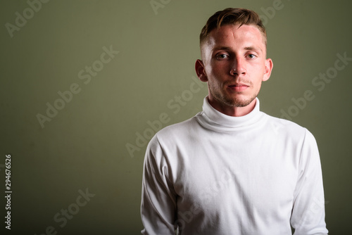 Young man wearing white turtleneck sweater against colored backg