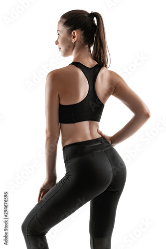 Brunette woman in black leggings, top and sneakers is posing isolated on white. Fitness, gym, healthy lifestyle concept.