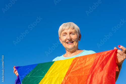 smiling senior woman with lgbt flag on blue background