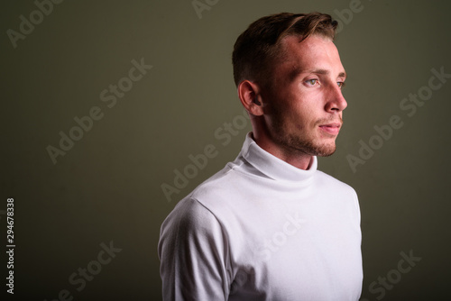 Young man wearing white turtleneck sweater against colored backg